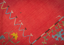 This Suzani was handmade during the early 20th century in Uzbekistan.
This suzani is composed of central floral motif embroidered in silk on an open red cotton field. Flanked by vibrant multi-tiered blossoming flowers to the right and left and framed by a lively floral meander. A multitude of colors are used for the embroidery, including turqoise, green, white, yellow, and purple. 