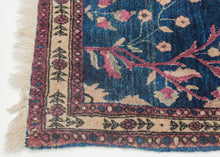 This Mohajeran Sarouk was handwoven during the first quarter of the 20th century. 
It features an imaginative tree of life design of a small cypress flanked by two whimsically intersecting trees bearing palmette-shaped "fruit" on an inky blue ground. . Plush and well-executed these best-of-type Sarouks are referred to as "Mohajeran". Thinly framed like a painting with a generously spaced floral main border flanked by minor borders of polychrome circles;This classically patterned rug should