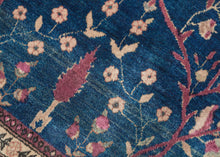 This Mohajeran Sarouk was handwoven during the first quarter of the 20th century. 
It features an imaginative tree of life design of a small cypress flanked by two whimsically intersecting trees bearing palmette-shaped "fruit" on an inky blue ground. . Plush and well-executed these best-of-type Sarouks are referred to as "Mohajeran". Thinly framed like a painting with a generously spaced floral main border flanked by minor borders of polychrome circles;This classically patterned rug should
