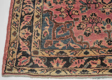 This Sarouk rug was handwoven during the second quarter of the 20th century. 
It features of an deep navy central medallion on a crimson ground. The field is filled with fine floral sprays and balanced by four scalloped cornices woven in light blue. The border is composed of a straightforward floral meander in the same deep navy almost black ground of the central medallion