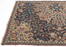 This rare and expressive Kurdish wagireh—or sampler rug—is a visual archive of design. Woven not for the market but as a reference tool, wagireh offered master weavers a compact way to preserve and transmit important elements of a pattern. Lush florals, scrolling vinery, and medallion fragments bloom in bold juxtaposition, floating across an asymmetrical field divided by tone and structure. The field’s deep indigo ground plays host to densely branched flowerheads and palmettes, while a large-scale ivory car