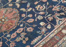 This piece showcases a graceful allover floral design anchored by a central medallion in soft rose and muted green tones. The generous borders, framed in sky blue and rust, add depth and contrast while highlighting the sophisticated floral latticework in the field. Finely woven with a dense, durable pile, this rug embodies the exceptional craftsmanship for which Sarouks are renowned