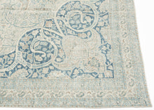 It features an elegant central medallion surrounded by flowing arabesques and floral tracery in delicate shades of sky blue, ivory, and soft taupe. The pale, airy palette and finely drawn design lend the piece a refined, almost ethereal quality that makes it versatile for both traditional and contemporary interiors. Framed by a scrolling vine border, this rug is a study in subtle sophistication and is a timeless decorative element for any space.