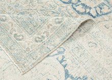 It features an elegant central medallion surrounded by flowing arabesques and floral tracery in delicate shades of sky blue, ivory, and soft taupe. The pale, airy palette and finely drawn design lend the piece a refined, almost ethereal quality that makes it versatile for both traditional and contemporary interiors. Framed by a scrolling vine border, this rug is a study in subtle sophistication and is a timeless decorative element for any space.