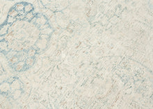 It features an elegant central medallion surrounded by flowing arabesques and floral tracery in delicate shades of sky blue, ivory, and soft taupe. The pale, airy palette and finely drawn design lend the piece a refined, almost ethereal quality that makes it versatile for both traditional and contemporary interiors. Framed by a scrolling vine border, this rug is a study in subtle sophistication and is a timeless decorative element for any space.