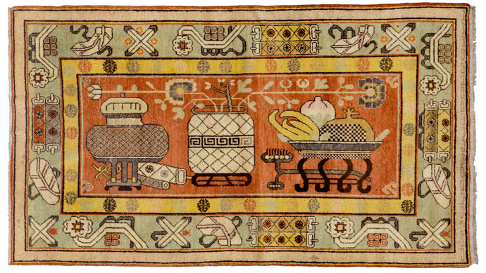Depiction of a bowl of fruit, a flower filled vase and various other auspicious symbols on a rich terracotta ground. The terracotta is nicely balanced by a but patinated celadon ground main border and a canary yellow ground minor border of repeating shou symbols. Shou is a very auspicious symbol that represents longevity. These rugs are often referred as 