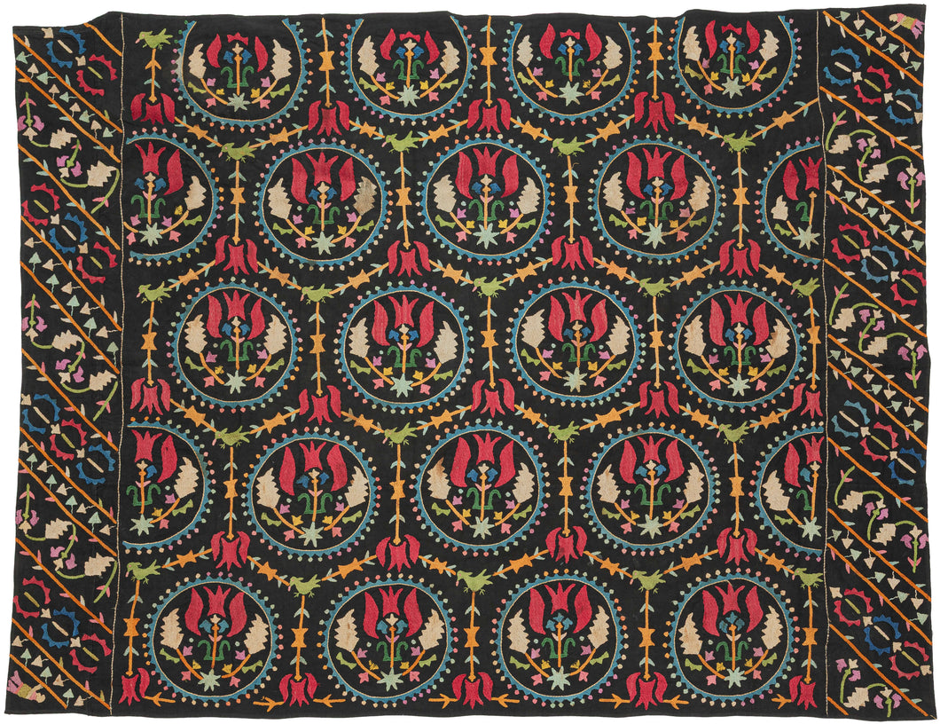 This embroidered textile is a well-preserved example of late Ottoman Armenian domestic needlework, likely produced in the town of Marash (modern-day Kahramanmaraş, Turkey) at the turn of the 20th century.  
The embroidery is executed in silk floss using satin and couching stitches across a black cotton ground.  It features concentric floral medallions, stylized birds and serrated leaves in lively blues, greens, red, pink, purple, yellow and ivory. Notably, two guardian-like anthropomorphic figure