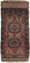 This Baluch rug was handwoven during the early 20th century in Afghanistan.
It features two octagonal Turkmen guls on a red ground and framed by a border of hourglass and cruciform shapes. Rich saturated tones and nice interplay between light and dark. It has original kilim ends on top and bottom that are each embellished with their own weft float pattern. This balisht has it's original kilim back still intact and which employs thick stripes of red, orange, brown and ivory.
