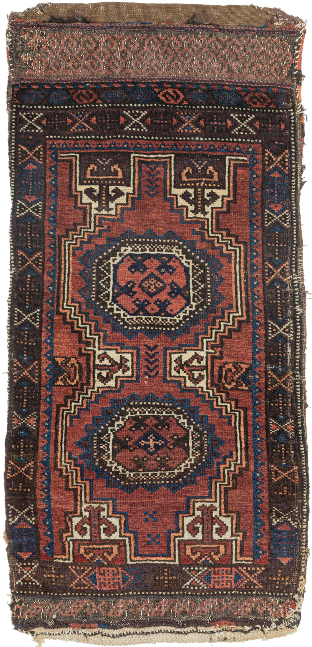 This Baluch rug was handwoven during the early 20th century in Afghanistan.
It features two octagonal Turkmen guls on a red ground and framed by a border of hourglass and cruciform shapes. Rich saturated tones and nice interplay between light and dark. It has original kilim ends on top and bottom that are each embellished with their own weft float pattern. This balisht has it's original kilim back still intact and which employs thick stripes of red, orange, brown and ivory.
