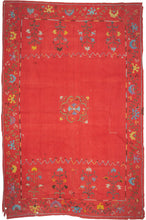 This Suzani was handmade during the early 20th century in Uzbekistan.
This suzani is composed of central floral motif embroidered in silk on an open red cotton field. Flanked by vibrant multi-tiered blossoming flowers to the right and left and framed by a lively floral meander. A multitude of colors are used for the embroidery, including turqoise, green, white, yellow, and purple.