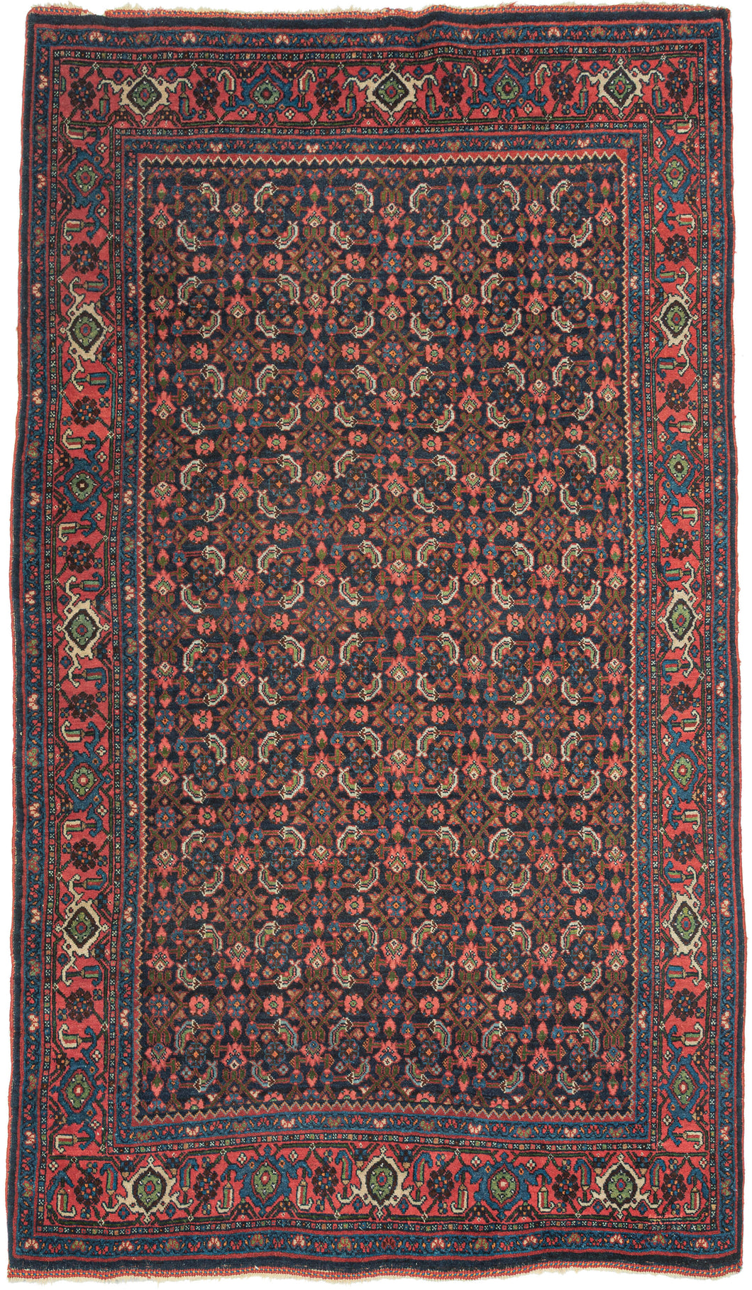 This Bidjar was handwoven during the second quarter of the 20th century.
It features an all-over herati patterned field in blues, reds, coral, ivory and green on a midnight blue backdrop. This bidjar lives up to its reputation as the