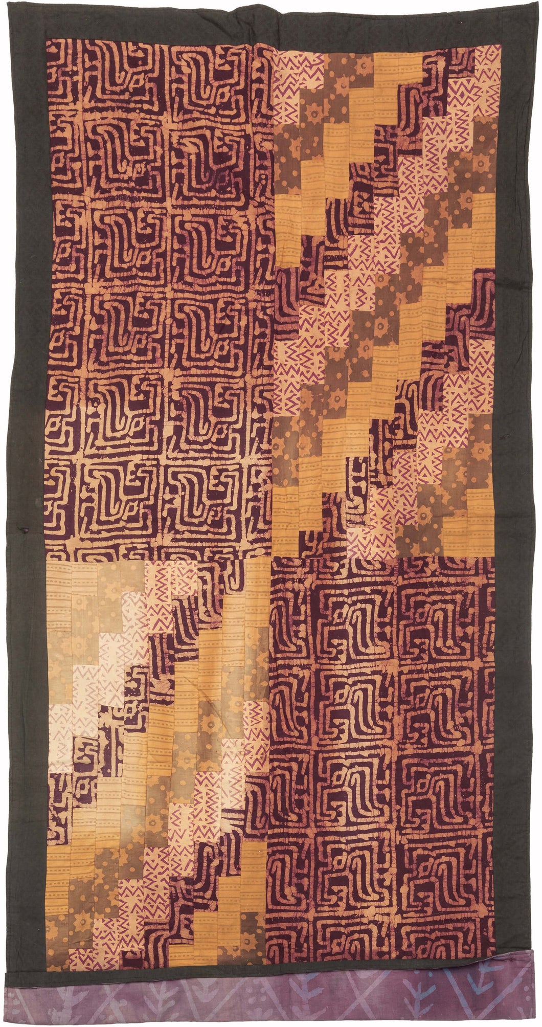 This batik patchwork was crafted in Indonesia during the 20th century.
Batik is a wax-resist technique that creates a distinctive style. This textile features a variety of batik designs that have been patchworked together into four quadrants creating a dynamic design in purples and yellows.
