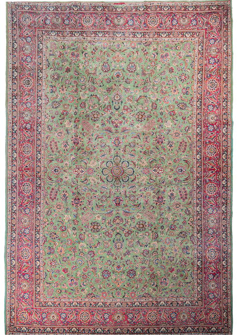 Keshan featuring an array of lively floral spray and detailed palmettes in pinks, blues and ivory atop a rare mint green field. The design has a central focus, but not quite a central medallion. A wide pink border encompasses the piece with an equally intricate pattern of scrolling leaves and 