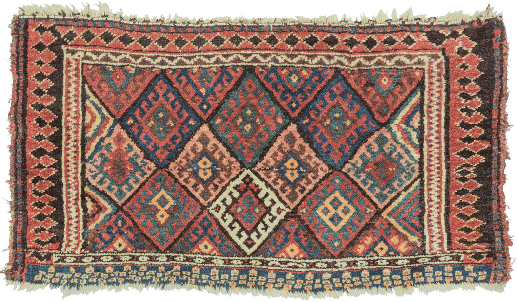 This bag face was woven by the Jaff Kurds of the Northern and Central Zagros mountains in Wester Iran during the late 19th century.  It features the classic Jaff interlocking diamond pattern in bright, cheerful colors. It is framed on three sides by a fun and wonky laleh abbasi border in black and red that becomes black triangles on a red ground before shifting back to laleh abbasi but with the colors reversed. The fourth side features red and white circles on an indigo ground.