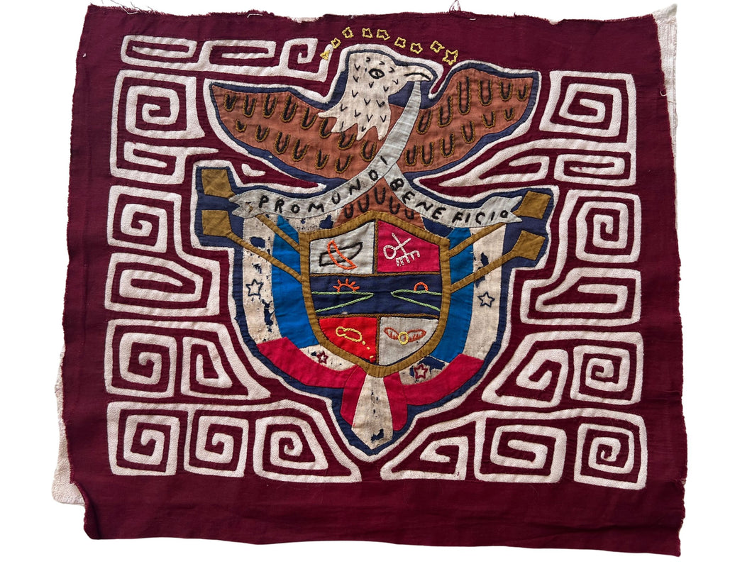 Vintage Mola cloth handmade by the Guna (previously spelled Kuna) people of the San Blas Islands.  Mola is a reverse appliqué technique, similar to the technique used in quilting but using multiple layers of different-colored cloth that are first sewn together before a design is created by cutting away different layers. These cloths are traditionally made in pairs tThis Mola features the Panamanian coat of arms with the words