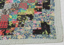 This vintage patchwork quilt was crafted in North America during the middle of the 20th century.
It features patch-worked squares of various fabric in rows of serrated stripes organized on the diagonal. Many of the squares feature there own detailed patterning which adds interest and touch of fun! Much of the stitching has been completed by hand included large visible running stitches in black giving the piece a kantha-like feel.
