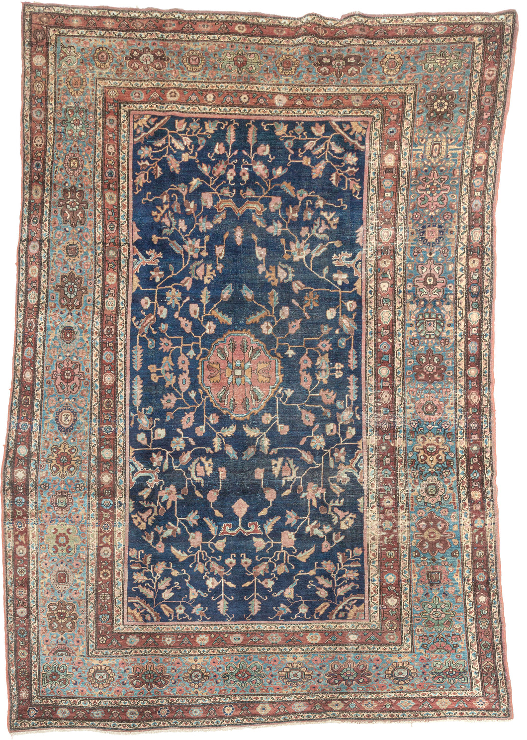 This piece showcases a graceful allover floral design anchored by a central medallion in soft rose and muted green tones. The generous borders, framed in sky blue and rust, add depth and contrast while highlighting the sophisticated floral latticework in the field. Finely woven with a dense, durable pile, this rug embodies the exceptional craftsmanship for which Sarouks are renowned
