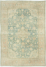 It features an ornate all-over design of muted palmettes and floral sprays in various soft shades of caramel, khaki and terracotta on an undulating indigo ground. It is framed by a border of alternating palmettes on meandering vines on a dusty peach ground. Very decorative, a soft, and elegant piece that will subtly elevate any space. washed out tabriz