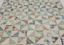 This vintage patchwork quilt was crafted in North America during the middle of the 20th century.
It features patch-worked grid composed of squares. Each square is formed of well balanced triangles of either colorful flannel patterns or more open dotted and striped cream ground patterning. The squares have been pieced together wondefully and the composition can be read many different ways that is accentuated by its perfectly square dimensions.