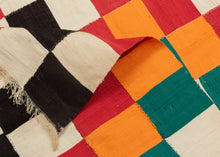 This blanket was likely woven by the Fulani people in Mali during the middle of the 20th century.
It was woven in multiple stripes which have been attached horizontally. It features an eye dazzling checkerboard composed of white, black, red, green, blue and a sunny yellow-orange. Four individual squares around the perimeter are woven with the red-yellow-green tricolor of the Malian flag.
Via The Metropolitan Museum of Art The checkerboard, a basic West African composition, ultimately may derive from