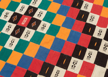 This blanket was likely woven by the Fulani people in Mali during the middle of the 20th century.
It was woven in multiple stripes which have been attached horizontally. It features an eye dazzling checkerboard composed of white, black, red, green, blue and a sunny yellow-orange. Four individual squares around the perimeter are woven with the red-yellow-green tricolor of the Malian flag.
Via The Metropolitan Museum of Art The checkerboard, a basic West African composition, ultimately may derive from