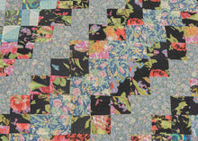 This vintage patchwork quilt was crafted in North America during the middle of the 20th century.
It features patch-worked squares of various fabric in rows of serrated stripes organized on the diagonal. Many of the squares feature there own detailed patterning which adds interest and touch of fun! Much of the stitching has been completed by hand included large visible running stitches in black giving the piece a kantha-like feel.