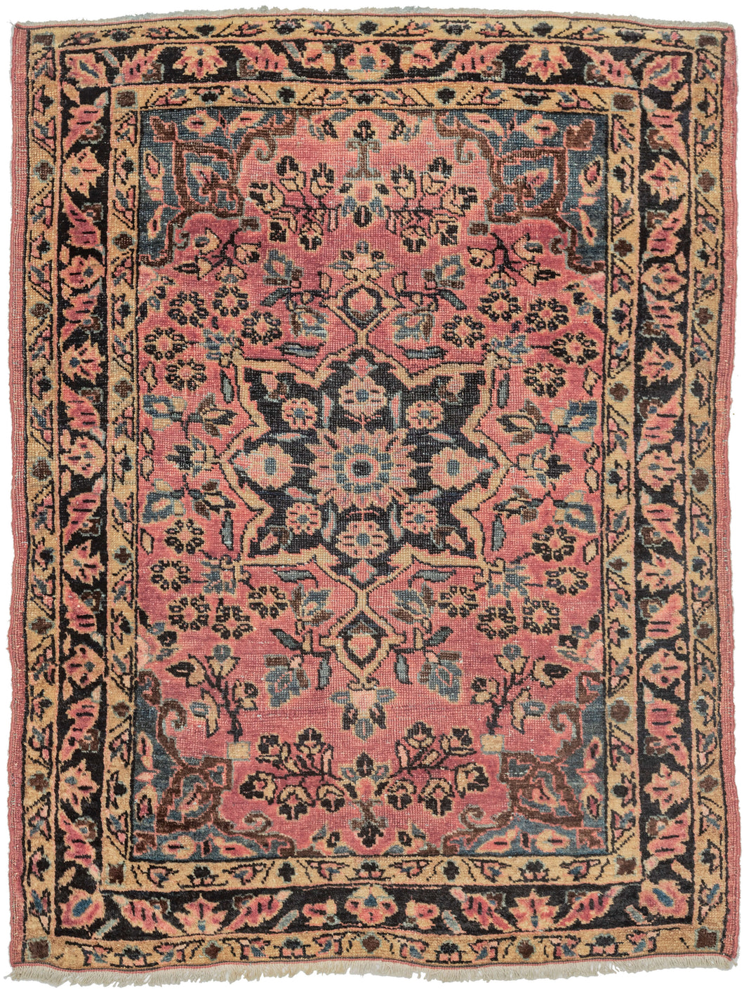 This Sarouk rug was handwoven during the second quarter of the 20th century.
It features of an deep navy central medallion on a crimson ground. The field is filled with fine floral sprays and balanced by four scalloped cornices woven in light blue. The border is composed of a straightforward floral meander in the same deep navy almost black ground of the central medallion