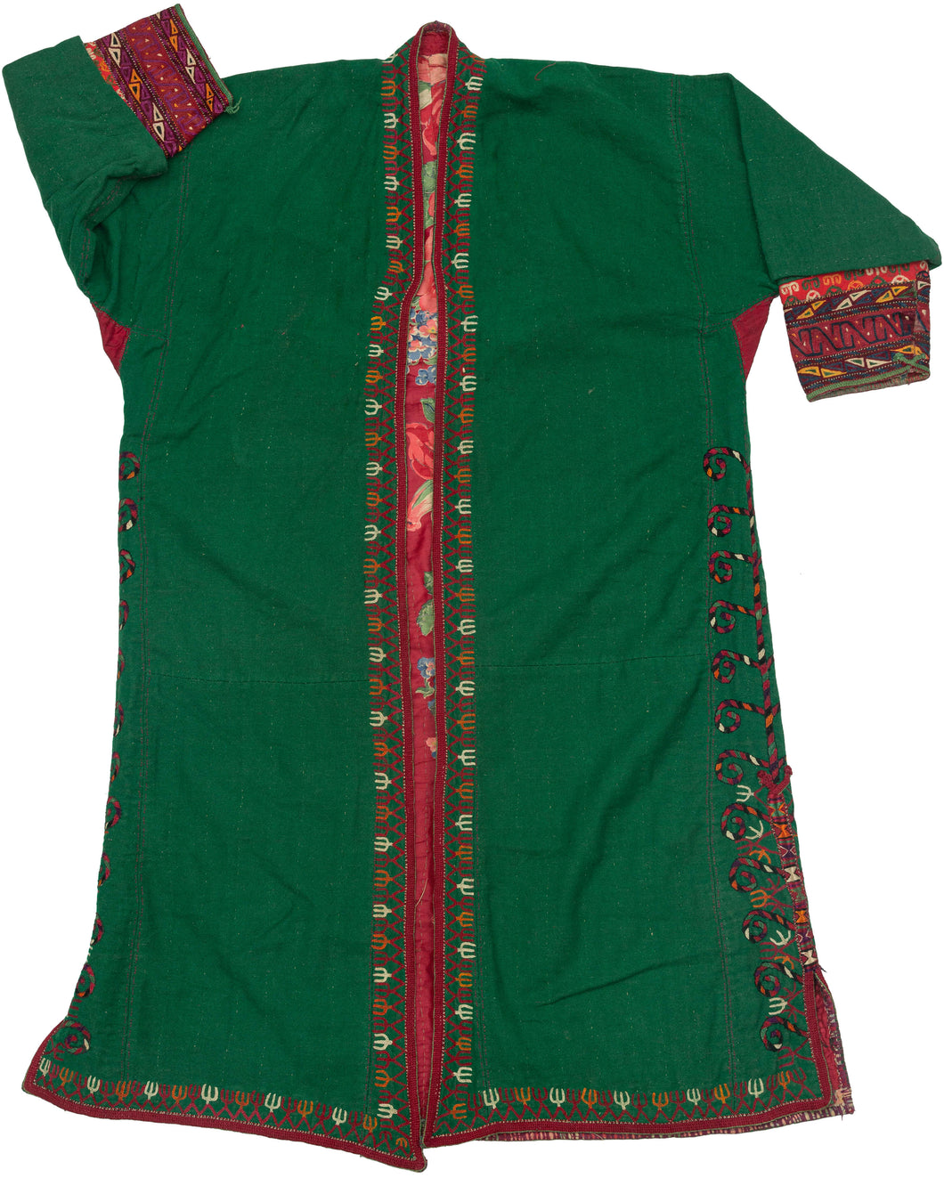 This lovely chapan is crafted from green wool. It is embroidered with an array of tones including black, red, white, orange and purple around its perimeter and up the sides. The tendrils of a tree of life or other plant form are found aroudn the slits on both sides. A red printed floral liner adds another element of interest.