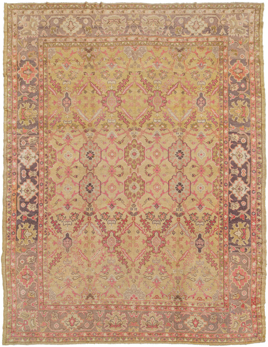 Antique Anatolian Oushak featuring an all-over design which is a combination of multiple lattice designs. A rare combination of bright pink, coral, soft olive, lilac, and lavender on a pale yellow ground gives this piece intrigue and calming energy. Perfectly framed by a palmette border that shifts from lavender to lilac with natural fading. A unique piece that is both collectible and highly decorative.