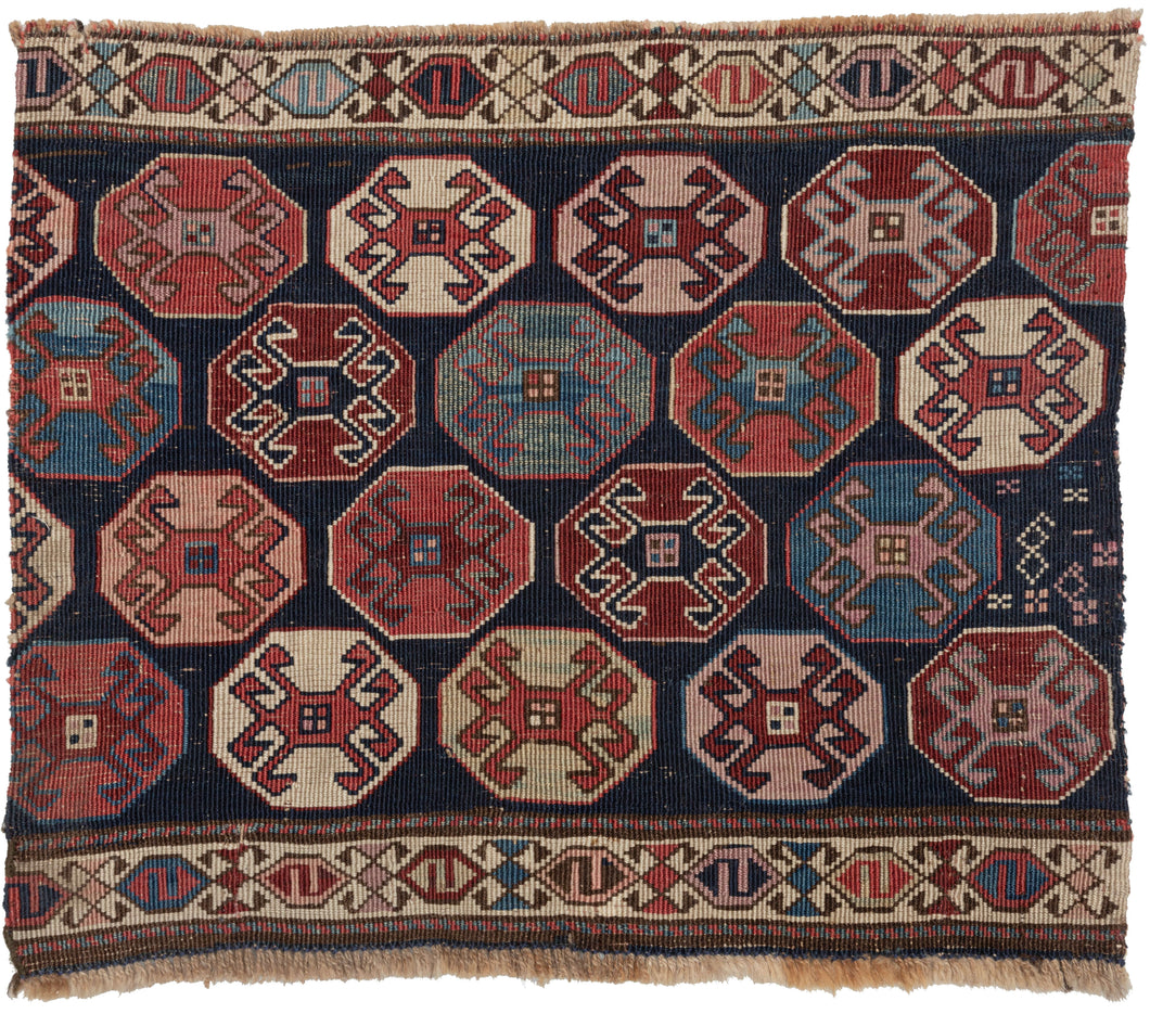 Antique NW Persian Shahsavan Mafresh fragment featuring a field of well-staggered octagons that float above a midnight blue ground. Each octagon is filled with a latch-hooked protection device in a spectacular range of contrasting but balanced tones of red, green, pink, purple, and blue. It is neatly framed on the top and bottom by thin and tight