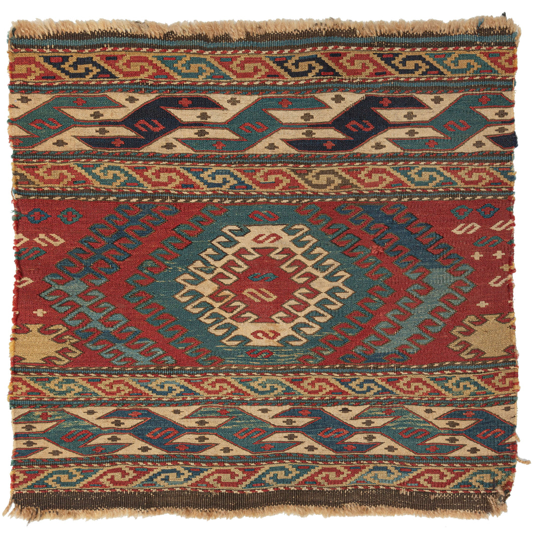 Antique Shahsavan Mafresh fragment featuring a central concentric latch hooked device in blues, green, and ivory on a red ground and flanked by strong and distinctive borders on top and bottom. Each segment features two minor borders of smooth