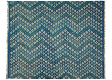 This Contemporary Maimana kilim was woven in Afghanistan during the 21st Century.  It features an allover field of rosette-like stepped diamonds in variations of greens, ivory, and gray that vibrate against the undulating jewel-toned blue ground.   In excellent condition, flat-woven with a substantial handle.