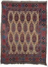 19th century Afshar masnad rug featuring a repeat field of cartouche-like devices on a sandy camel field. The devices are outlined in greens and soft blues filled with flowering vases on red ground. The whole is framed by a small inner border of diagonal stripes and a bigger main border of large scale rosettes alternating in blue, red, and black rosettes.