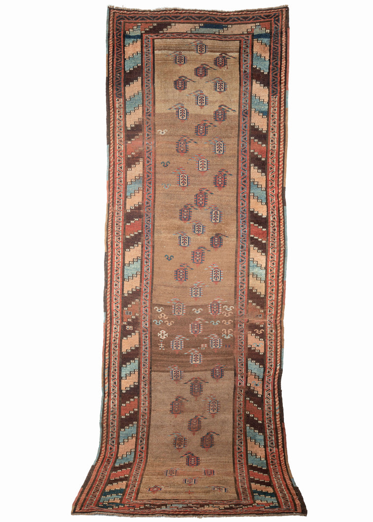 19th century Kurdish runner featuring a pattern of sparse and asymmetrically organized botehs in dark and light blues, apricot, and madder on a plush, variegated camel field. Abstracted figures and shapes which are likely the weaver and a rendition of bats or birds can be found near the center. A colorful main border of wide diagonal stripes more commonly found in Kurdish bag faces energizes the composition and adds additional distinction. 