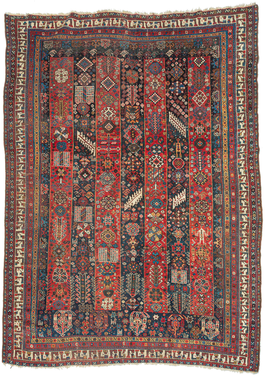 An exceptional Shekarlu rug with an unusually elaborate striped field, alternating saturated madder-red and deep indigo panels packed with an astonishing vocabulary of small motifs. Trees, rosettes, comb-like devices, lattices, geometric medallions, animals, and tiny human figures appear almost like a woven archive of tribal imagery, with scarcely an inch left unconsidered.