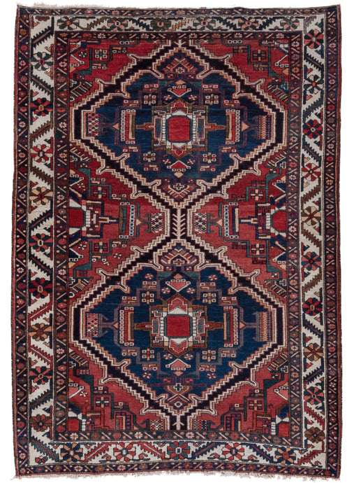 This rug is composed of two navy medallions on a rich red ground. A dark brown flanked by white and orange zigs and zags around both medallions adding some electricity. The main border is composed of rosettes and serrated leave.  A hard to find size for Bakhtiaris of this type.