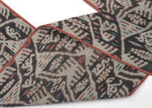 

A striking West Timor cotton ikat featuring rhythmic ancestral and vegetal motifs arranged in a vertical progression. Deep brown-black and soft ivory form the primary contrast, accented by subtle coral and indigo details that animate the surface.

The repeating abstracted figural forms and branching motifs reflect Timorese ceremonial weaving traditions, executed in warp ikat with characteristic feathered edges. Finished with traditional fringe and side bindings.