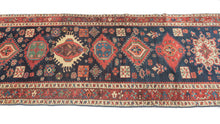 Karadagh It features a series of nested medallions that march down a rich abrashed indigo field. The medallions are rendered in blues, green, red, apricot and aubergine with geometric symbols and figures filling out the negative space. The pile is low and of lush high quality wool.