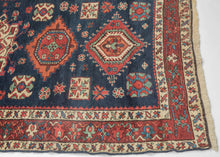 Karadagh It features a series of nested medallions that march down a rich abrashed indigo field. The medallions are rendered in blues, green, red, apricot and aubergine with geometric symbols and figures filling out the negative space. The pile is low and of lush high quality wool.