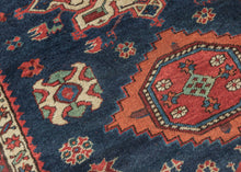 Karadagh It features a series of nested medallions that march down a rich abrashed indigo field. The medallions are rendered in blues, green, red, apricot and aubergine with geometric symbols and figures filling out the negative space. The pile is low and of lush high quality wool.