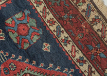 Karadagh It features a series of nested medallions that march down a rich abrashed indigo field. The medallions are rendered in blues, green, red, apricot and aubergine with geometric symbols and figures filling out the negative space. The pile is low and of lush high quality wool.