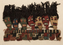 This Pre-Columbian textile fragment dates to the Wari period (circa 600–1000 AD).

It features a striking row of anthropomorphic head motifs with dramatic black wool tufts, likely once serving as the decorative fringe of an elite garment or ceremonial textile. The figures, worked in shades of cochineal red, green, gold, and deep indigo, are a hallmark of Wari iconography and exhibit the sophisticated interlinking knit structure that this Andean culture pioneered.

The fragment remains in very good condition