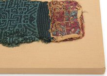 This Pre-Columbian textile fragment dates to the Wari period (circa 600–1000 AD) and is believed to be a panel from an elite tunic, serving as a form of rank insignia.

The design features a bold, labyrinthine geometric motif in tone on tone indigo and turqoise offset by remnants of a multicolor section in cochineal red, gold, and turquoise. These complex patterns are emblematic of Wari statecraft, where textiles conveyed status, authority, and identity.&nbsp;Technically, this piece exemplifies the Wari mas