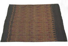 This elegant silk pha sin or traditional tube skirt was handmade northeast Thailand during the middle of the 20th century.

It is a masterful example of mudmee (ikat) weaving from the Isaan region. Woven entirely from fine silk, the textile features a mesmerizing field of diamond motifs arranged in vertical zigzag bands, subtly interlaced with red, gold, and deep aubergine tones against a near-black ground. The effect is one of shimmering depth and rhythmic precision.

The upper and lower bands (hua sinh an