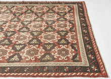 It features a striking allover lattice design with repeating floral rosettes and angular motifs in a balanced palette of earthy terracotta, chocolate brown, ivory, and soft blue. The wide border, decorated with stylized stars and angular vine elements, frames the field beautifully, adding depth and structure to the pattern. The bold yet harmonious composition and soft tones exemplify the sophisticated village weaving traditions of the region.