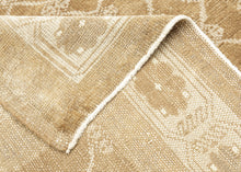 KURD Its warm camel field is animated by a playfully wonky interlocking lattice and framed by a border of larger floral medallions in soft ivory and beige. The lattice has the feel of a bent and distorted chain link fence. The delightful irregularity in the design has an endearing quality that speaks to its handmade nature and gives the piece a unique, almost whimsical character. The washed out neutral palette and subtle abrash create a natural warmth, making it a versatile choice for both traditional and c