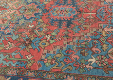 This classic Heriz features a geometric central medallion&nbsp;set against a richly layered field of angular vines, stylized leaves, and geometric blossoms.&nbsp;The palette is both vibrant and balanced with coral and madder reds forming the backdrop, while sky blue and deep indigo provide striking contrast. Soft accents of ivory, green, and gold animate the details, giving the rug a depth and luminosity.