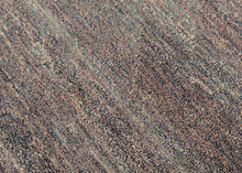 This unusual Chinese rug reflects an inventive approach to material reuse and modern design. Its oval shape and softly variegated surface are woven from a blend of reclaimed yarns to create a subtle, almost painterly texture that shifts between muted mauve, slate, and mineral blue tones. The fine mosaic of color and understated abstraction evoke the spirit of Art Deco modernism while remaining deeply tactile and organic