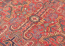 This Heriz rug was handwoven during the second quarter if the 20tb century.&nbsp;

It features an allover field filled with branching angular motifs, stylized palmettes, stepped forms, and curling leaves radiating around a compact medallion. The palette is warm and vibrant, anchored by a rich madder-red ground accented with deep indigo, sky blue, saffron and ivory. The contrast between the crisp drawing and saturated dyes gives the rug a powerful architectural presence without feeling heavy. A beautifully d