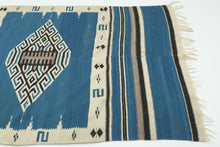 This serape was handwoven in central Mexico during the middle of the 20th century.

A luminous Texcoco serape distinguished by its saturated indigo field and a well articulated central diamond medallion. The stepped, labyrinthine geometry—woven in crisp natural white and deep black creates a powerful visual anchor, while the serrated motifs and butterfly-like accents along the border add nice rhythmic movement.